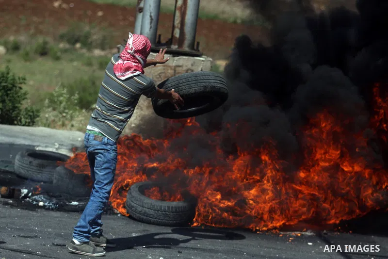 A Palestinian protester burns a tire, during clashes on Nakba Day near Ofer prison, near Ramallah, the West Bank, 15 May 2012. Thousands marched in the West Bank and Gaza Strip, commemorating the dispersal of hundreds of...