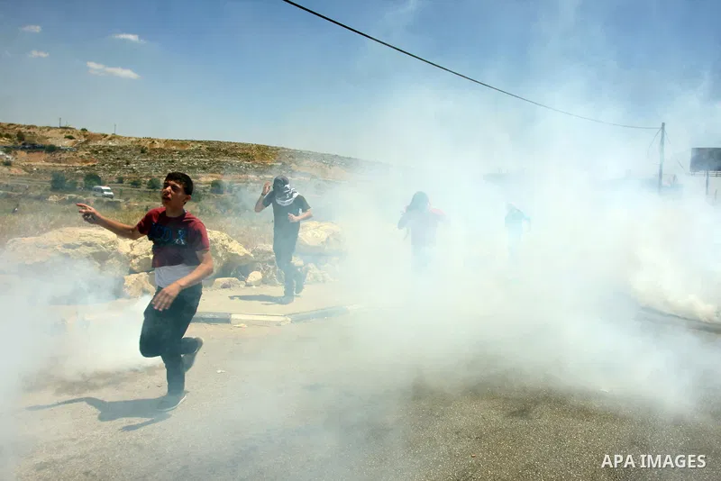 Palestinian stone throwers try to avoid tear gas fired by Israeli soldiers, during clashes on Nakba Day near Ofer prison, near Ramallah, the West Bank, 15 May 2012. Thousands marched in the West Bank and Gaza Strip, comm...