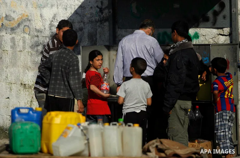 Palestinian children filling plastic bottles and jerry cans with drinking water from a public tap in the southern Gaza Strip refugee camp of Rafah on May 16, 2012. Photo by Eyad Al Baba