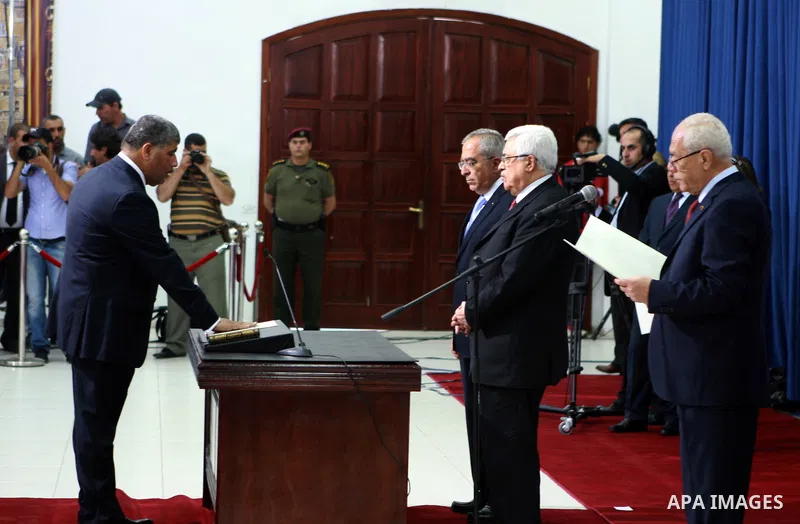 Palestinian National Authority President Mahmoud Abbas and his Prime Minister Salam Fayyad, receive the new government Ministers during the swearing in ceremony of the new cabinet, at Abbas's headquarters in the West Ban...