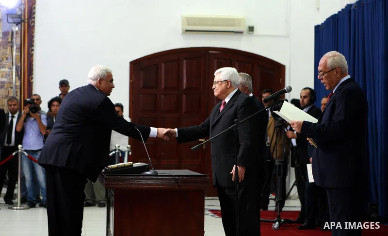 Palestinian National Authority President Mahmoud Abbas and his Prime Minister Salam Fayyad, receive the new government Ministers during the swearing in ceremony of the new cabinet, at Abbas's headquarters in the West Ban...