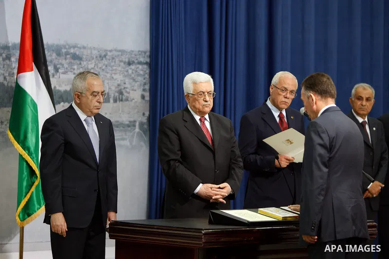 Palestinian National Authority President Mahmoud Abbas and his Prime Minister Salam Fayyad, receive the new government Ministers during the swearing in ceremony of the new cabinet, at Abbas's headquarters in the West Ban...