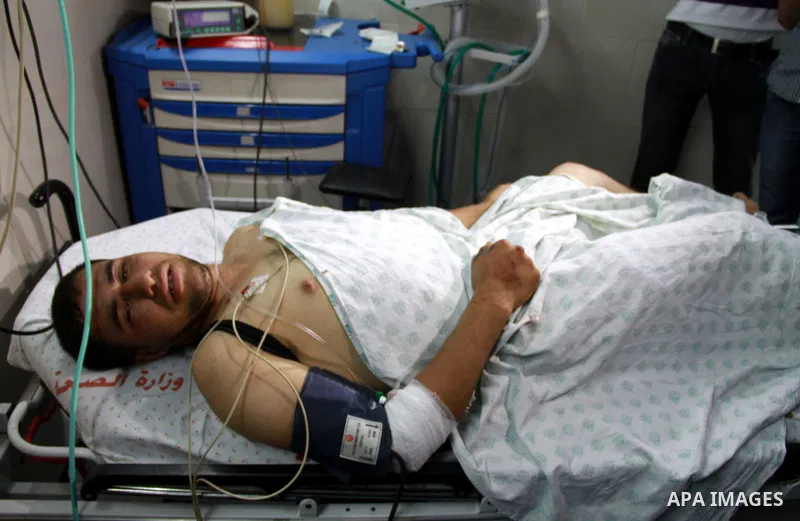 Palestinian medics receive a wounded man for treatment at a hospital in Gaza City on May 17, 2012, following Israeli shelling into the Gaza Strip in which seven people were wounded, two of them in critical condition, nea...