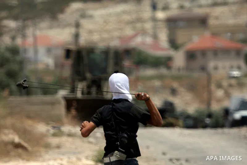 Palestinians throw rocks at an Israeli army bulldozer during clashes in the northern West Bank village of Kufr Qaddum, near the Jewish settlement of Kdumim, Friday, May 18, 2012. Photo by Wagdi Eshtayah