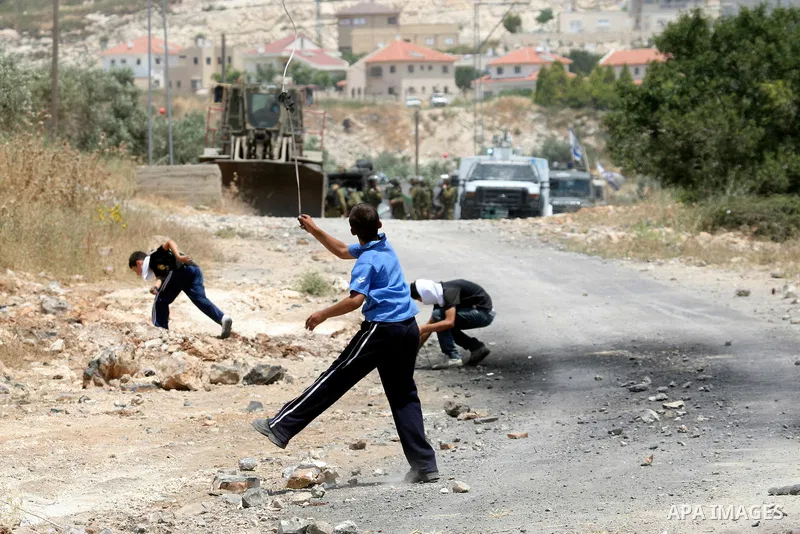 Palestinians throw rocks at an Israeli army bulldozer during clashes in the northern West Bank village of Kufr Qaddum, near the Jewish settlement of Kdumim, Friday, May 18, 2012. Photo by Wagdi Eshtayah
