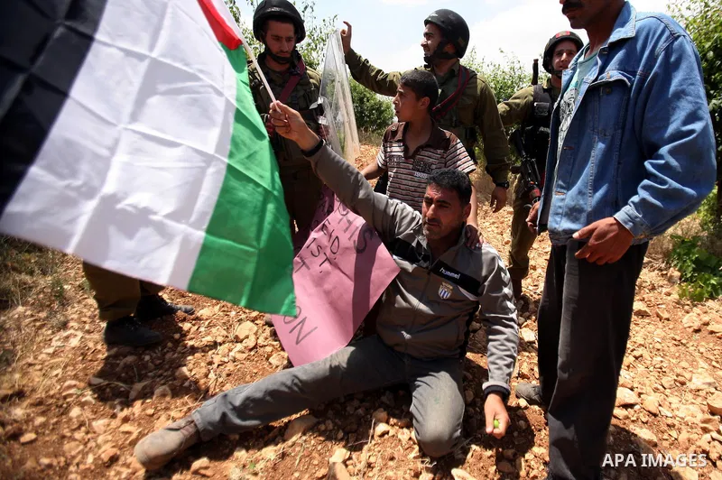Palestinians wave their national flag during a demonstration a protest in Beit Amer village, north of the West Bank town of Hebron, on May 19, 2012 where Israeli soldiers tried to evacuate demonstrators by force and arre...