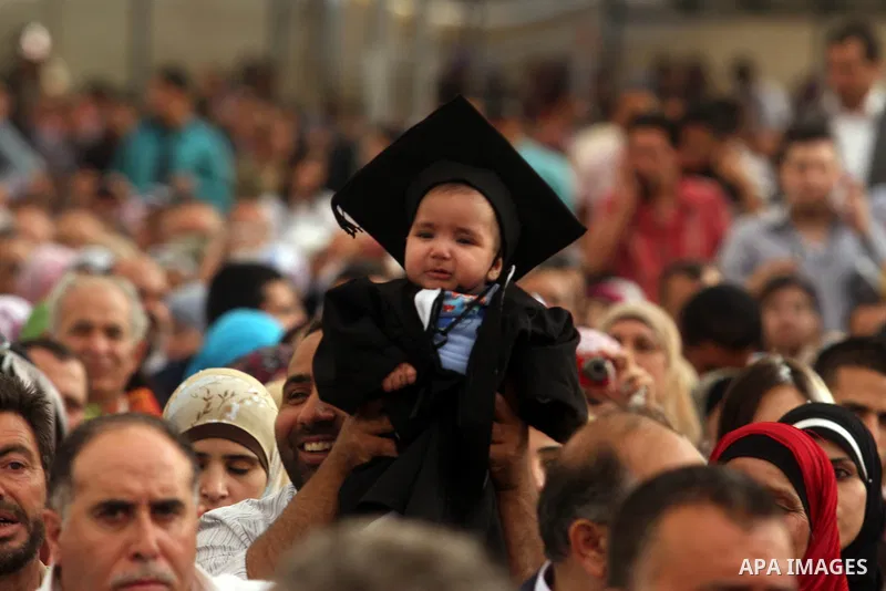 A Palestinian child wears a costume graduation, during the graduation ceremony at the Birzeit University near the West Bank city of Ramallah. as some 3000 students received their degrees at the end of the academic year o...