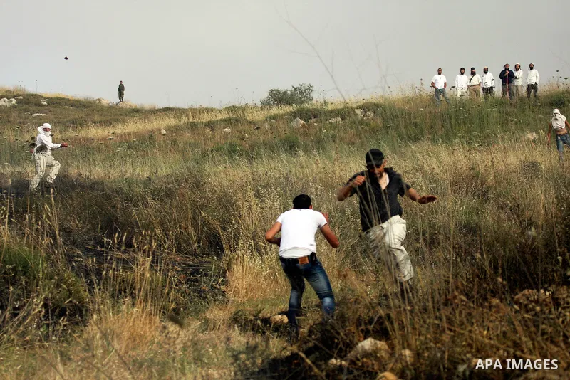 Israeli settlers from the Jewish settlement of Yitzhar throw stones during clashes with Palestinians from the village of Asira al-Qibiliya, south of the northern West Bank city of Nablus on May 19, 2012. The Israeli army...