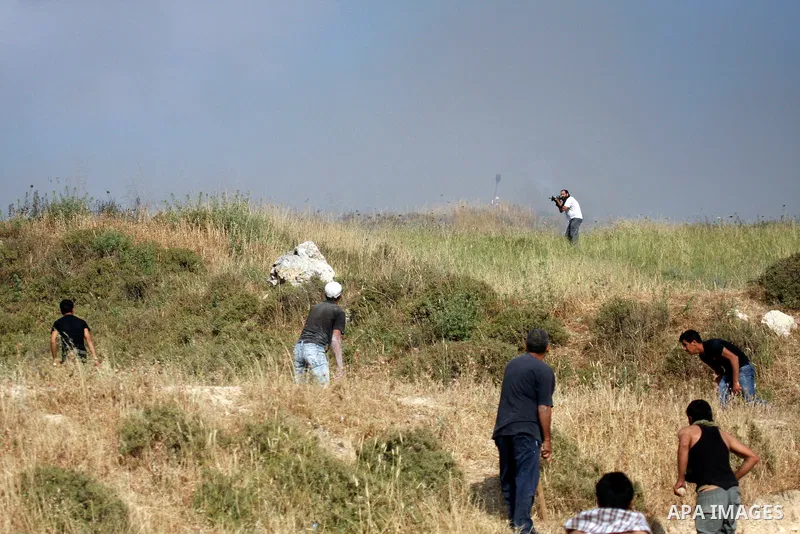 Palestinians from the village of Asira al-Qibiliya throw stones during clashes with Israeli settlers from the Jewish settlement of Yitzhar, south of the northern West Bank city of Nablus on May 19, 2012. The Israeli army...