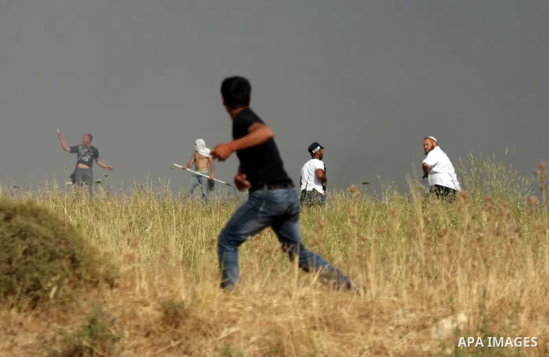 A Palestinians man from the village of Asira al-Qibiliya throws stones during clashes with Israeli settlers from the Jewish settlement of Yitzhar, south of the northern West Bank city of Nablus on May 19, 2012. The Israe...