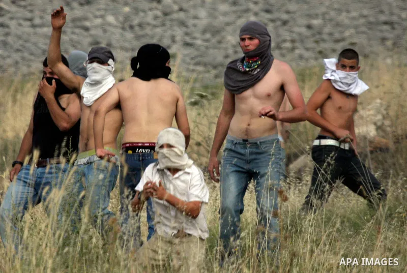 Israeli settlers from the Jewish settlement of Yitzhar throw stones during clashes with Palestinians from the village of Asira al-Qibiliya, south of the northern West Bank city of Nablus on May 19, 2012. The Israeli army...