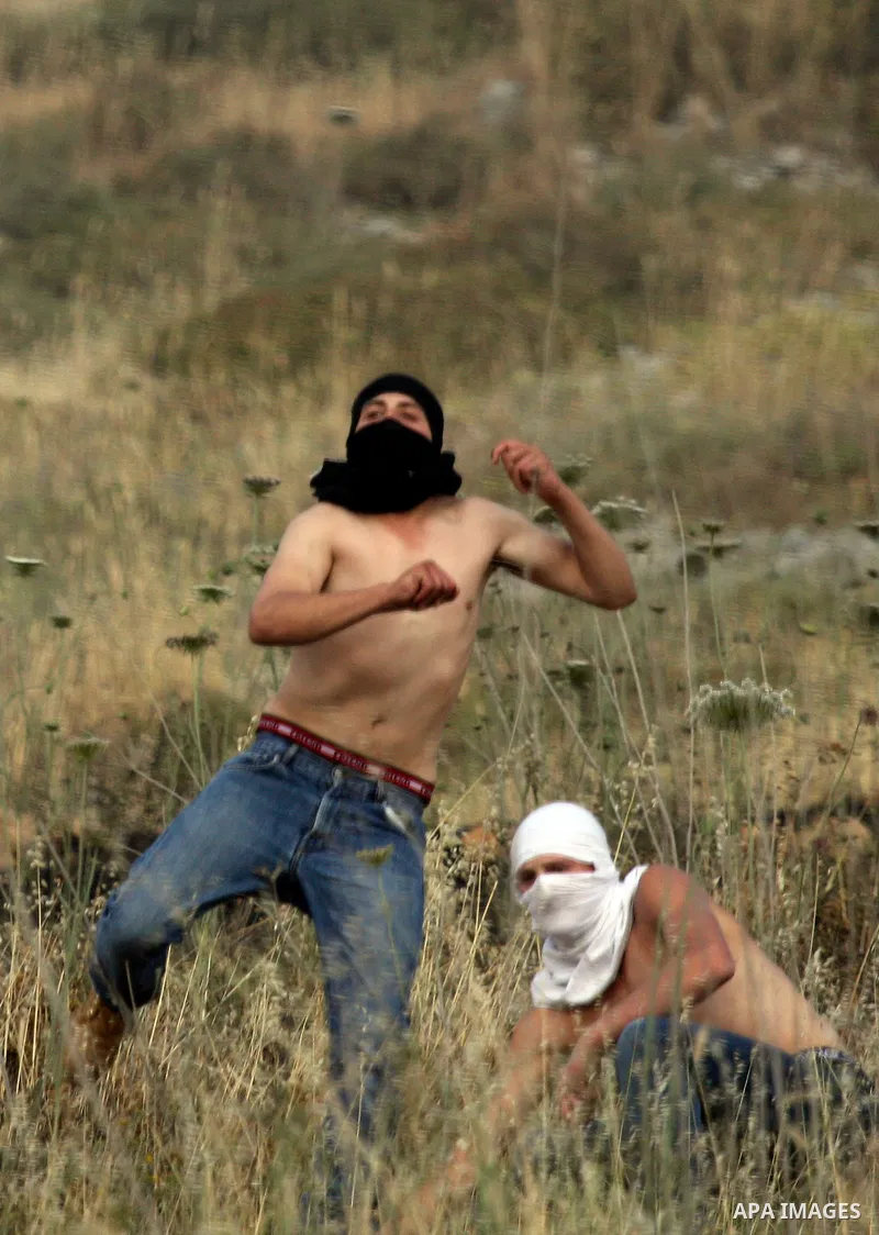 Israeli settlers from the Jewish settlement of Yitzhar throw stones during clashes with Palestinians from the village of Asira al-Qibiliya, south of the northern West Bank city of Nablus on May 19, 2012. The Israeli army...