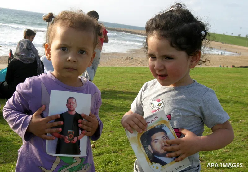 Palestinian children prisoners hold pictures of relatives held in an Israeli jail during tourist trip in the West Bank city of Jaffa, on May 19 2012. Photo by Mahfouz Abu Turk