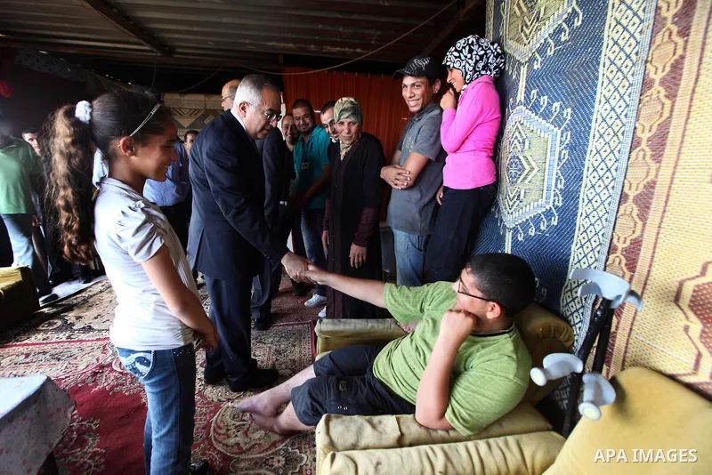 Palestinian Prime Minister Salam Fayyad, visits Om Rami Fatila's house in Tulkarm Governorate, in the West Bank on May 21, 2012. Photo by Mustafa Abu Dayeh