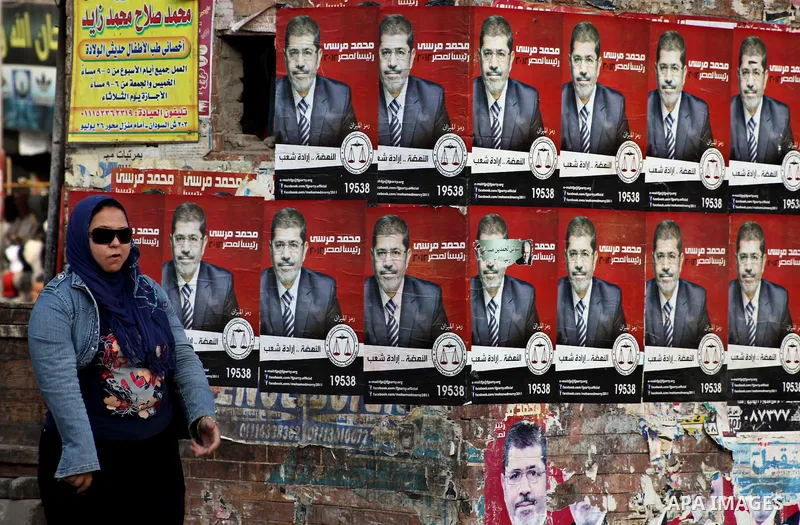 An Egyptian woman walks past election campaign posters for the Muslim Brotherhood's presidential candidate, Mohammed Mursi, in Cairo on May 21, 2012. The Supreme Council of the Armed Forces urged Egyptians to accept the...