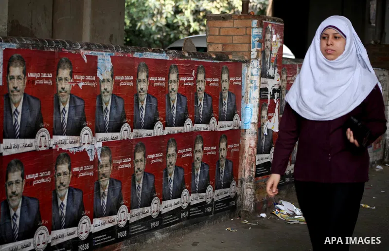 An Egyptian woman walks past election campaign posters for the Muslim Brotherhood's presidential candidate, Mohammed Mursi, in Cairo on May 21, 2012. The Supreme Council of the Armed Forces urged Egyptians to accept the...