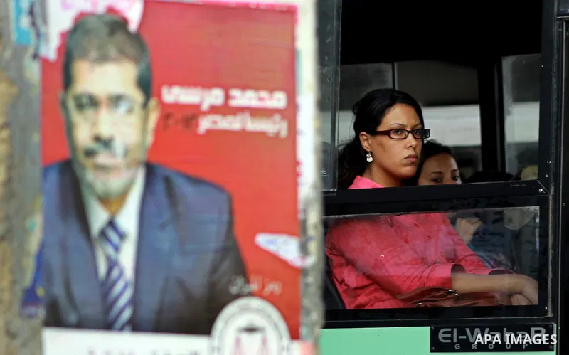 An Egyptian woman in a bus behind election campaign posters for the Muslim Brotherhood's presidential candidate, Mohammed Mursi, in Cairo on May 21, 2012. The Supreme Council of the Armed Forces urged Egyptians to accept...