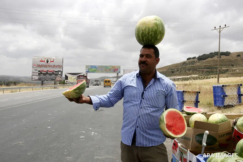 A Palestinian fruit vendors balance watermelons on their head as they try to attract customers in the West Bank town of Nablus near Hawara checkpoint, on May 22, 2012. Photo by Wagdi Eshtayah