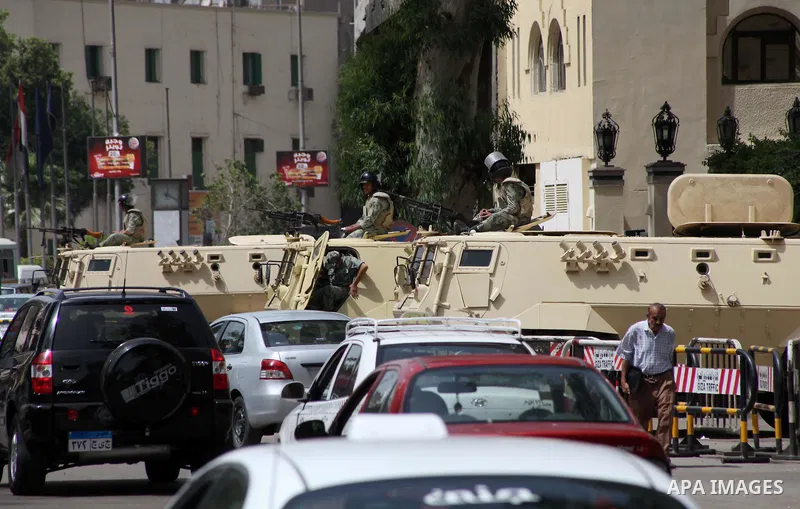 Egyptians walk in front of an army vehicle , in Cairo on May 22, 2012, one day before the country's landmark presidential elections. A buzz of excitement swept through Cairo, a day before its first presidential election...