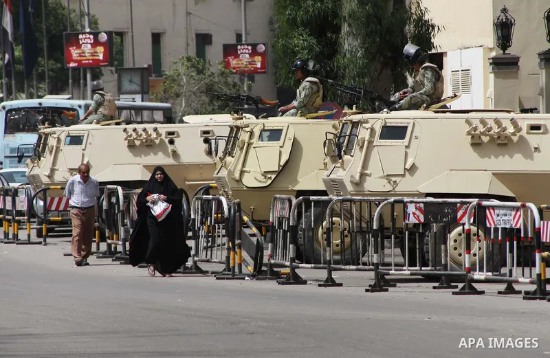 Egyptians walk in front of an army vehicle , in Cairo on May 22, 2012, one day before the country's landmark presidential elections. A buzz of excitement swept through Cairo, a day before its first presidential election...