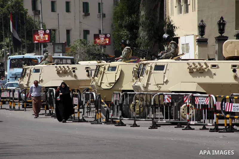 Egyptians walk in front of an army vehicle , in Cairo on May 22, 2012, one day before the country's landmark presidential elections. A buzz of excitement swept through Cairo, a day before its first presidential election...