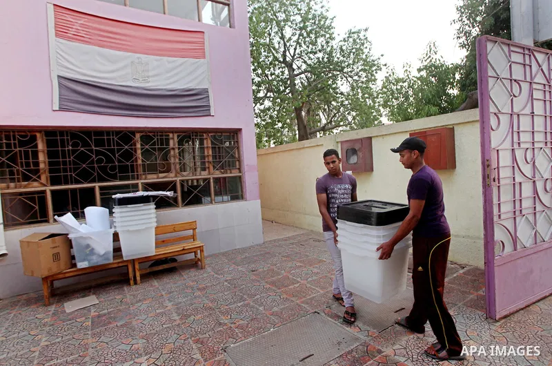 Egyptian workers carry empty ballot boxes to a polling station in the Coptic neighbourhood of Manshiyet Nasser in Cairo on May 22, 2012. A buzz of excitement swept through the Egyptian capital a day before its first pres...