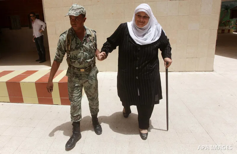Egyptian security man helps a woman to casting her ballot in the first round of Egypt's presidential elections, at a polling station in Cairo, Egypt, 23 May 2012. Egyptian voters, on 23 May, queued at polling stations fo...