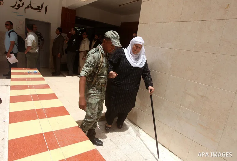 Egyptian security man helps a woman to casting her ballot in the first round of Egypt's presidential elections, at a polling station in Cairo, Egypt, 23 May 2012. Egyptian voters, on 23 May, queued at polling stations fo...