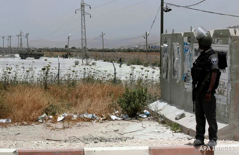 An Israeli soldier looks at a blindfolded and handcuffed Palestinian youth, as he sits in the back of a car after he was arrested at the Hawara checkpoint on the southern edge of the northern Palestinian city of Nablus i...