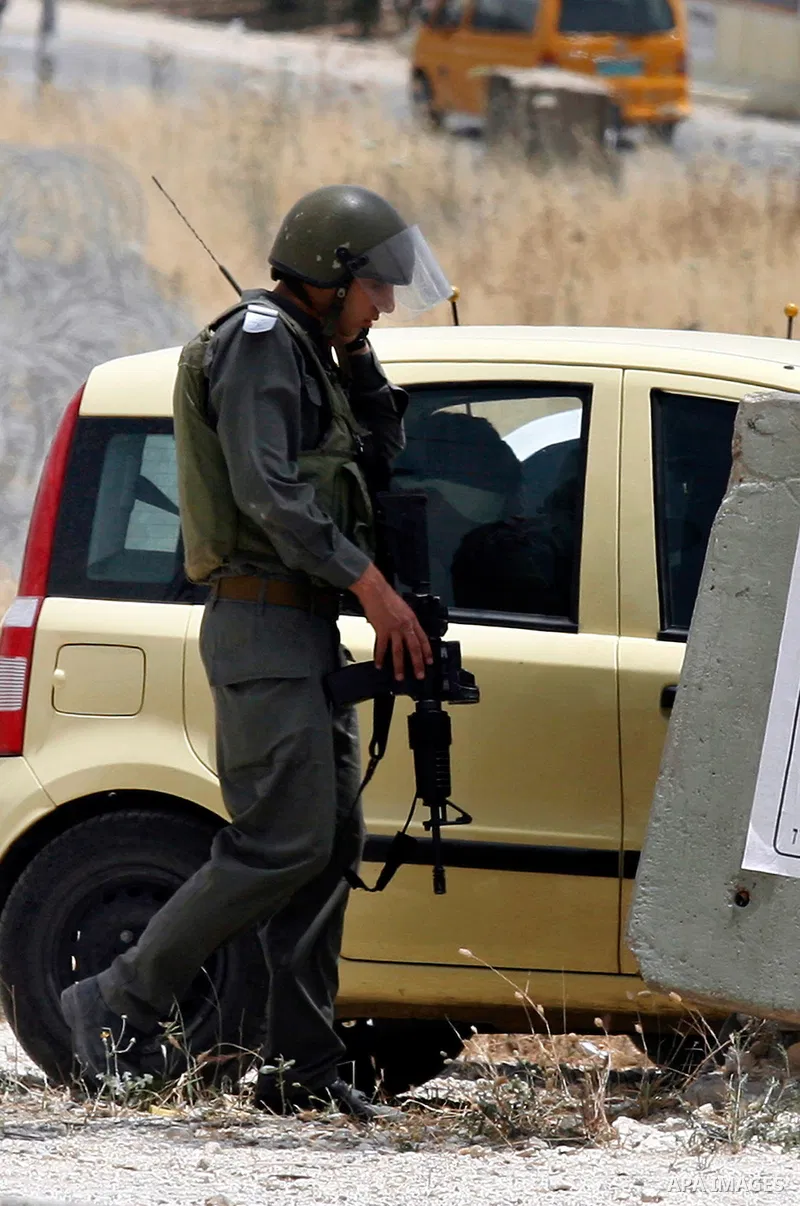 An Israeli soldier looks at a blindfolded and handcuffed Palestinian youth, as he sits in the back of a car after he was arrested at the Hawara checkpoint on the southern edge of the northern Palestinian city of Nablus i...