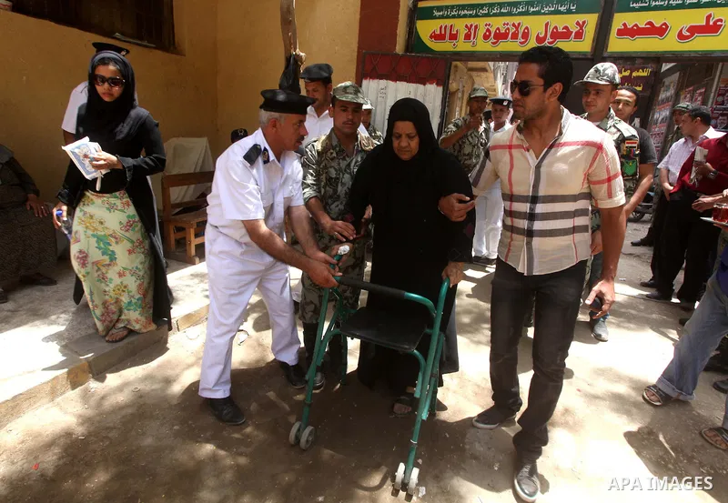 Egyptian policeman helps a woman to vote during second day of the first round of Egypt's presidential elections in Cairo, Egypt, 24 May 2012. Media reports quoting state-television and observers said that far less Egypti...
