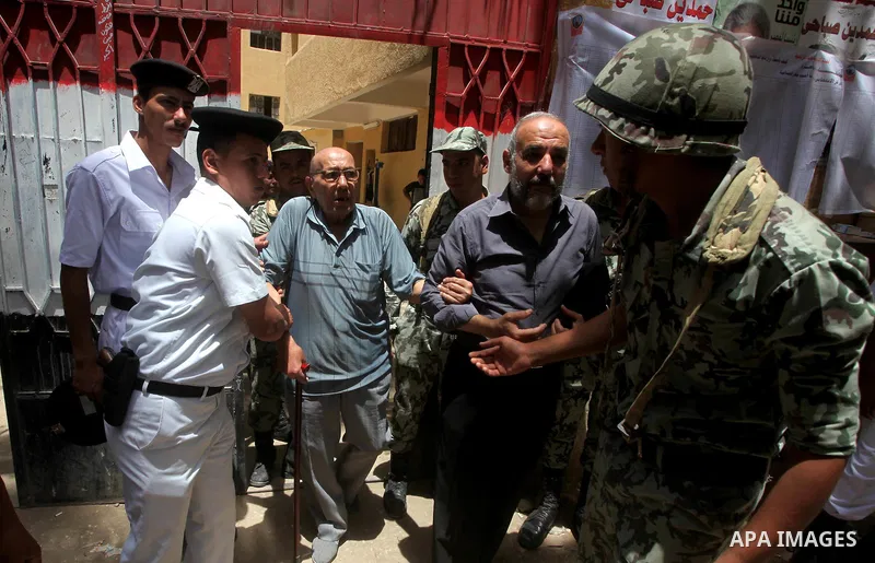 Egyptian policemen help a handicapped man to vote during second day of the first round of Egypt's presidential elections in Cairo, Egypt, 24 May 2012. Media reports quoting state-television and observers said that far le...