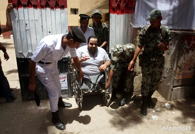 Egyptian policemen help a handicapped man to vote during second day of the first round of Egypt's presidential elections in Cairo, Egypt, 24 May 2012. Media reports quoting state-television and observers said that far le...
