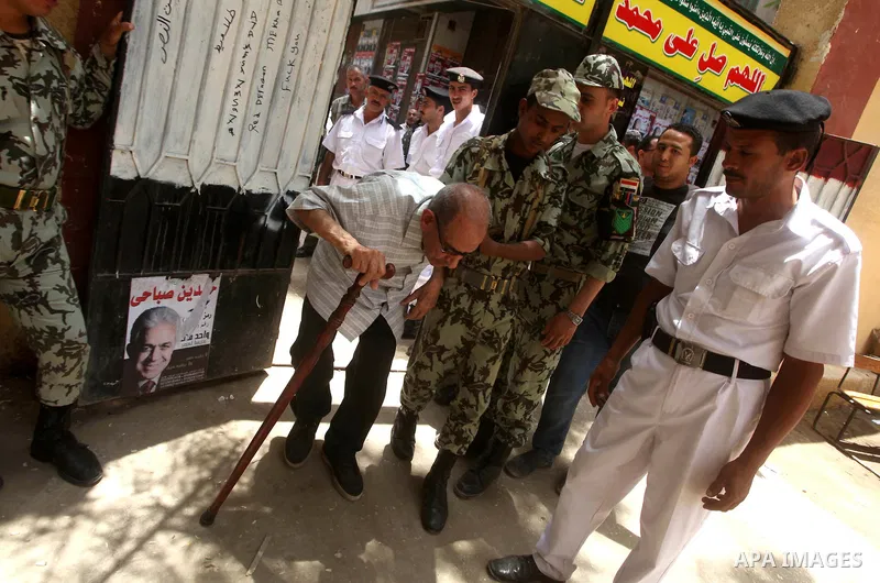 Egyptian policemen help a old man to vote during second day of the first round of Egypt's presidential elections in Cairo, Egypt, 24 May 2012. Media reports quoting state-television and observers said that far less Egypt...