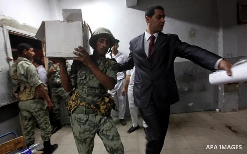 An Egyptian policeman takee sealed ballet box for the election officials to count ballots of the first round of Egypt's presidential elections, in a polling station in Cairo, Egypt, at the end of the election's second da...