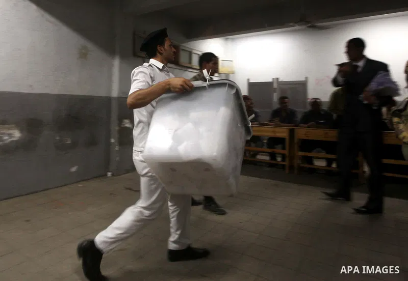 An Egyptian policeman takee sealed ballet box for the election officials to count ballots of the first round of Egypt's presidential elections, in a polling station in Cairo, Egypt, at the end of the election's second da...
