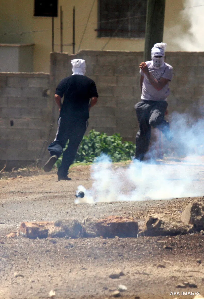 Palestinian protesters run away from tear gas during clashes in the northern West Bank village of Kufr Qaddum, near the Jewish settlement of Kdumim, on May 25, 2012. Photo by Wagdi Eshtayah