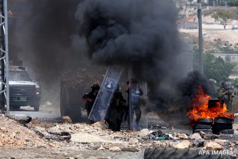 Israeli soldiers wearing gas masks walk through black smoke rising from burning tyres during clashes in the northern West Bank village of Kufr Qaddum, near the Jewish settlement of Kdumim, on May 25, 2012. Photo by Wagdi...