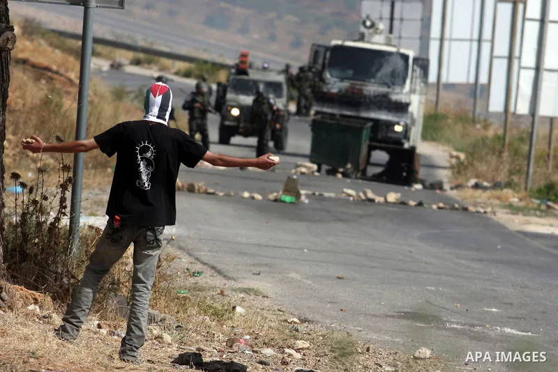 A masked Palestinian protester hurls stones during clashes between stone throwers and Israeli soldiers in the West Bank village of Nabi Saleh, near Ramallah, on May 25, 2012 following a protest against the confiscation o...