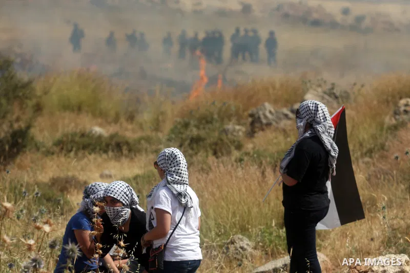 Masked Palestinian protesters hold national flag during clashes between stone throwers and Israeli soldiers in the West Bank village of Nabi Saleh, near Ramallah, on May 25, 2012 following a protest against the confiscat...