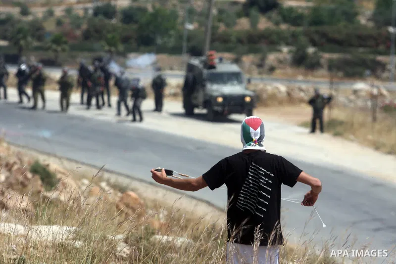 A masked Palestinian protester hurls stones during clashes between stone throwers and Israeli soldiers in the West Bank village of Nabi Saleh, near Ramallah, on May 25, 2012 following a protest against the confiscation o...