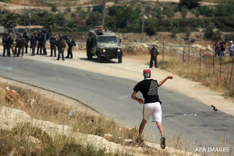 A masked Palestinian protester hurls stones during clashes between stone throwers and Israeli soldiers in the West Bank village of Nabi Saleh, near Ramallah, on May 25, 2012 following a protest against the confiscation o...