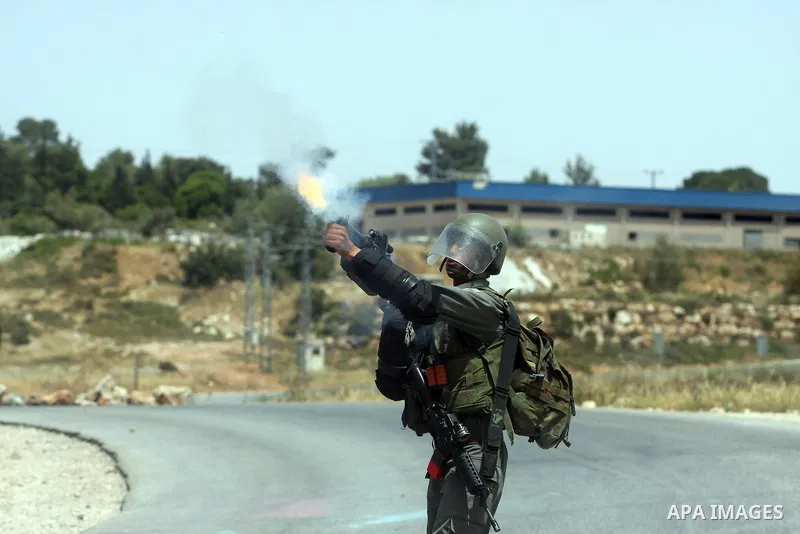Israeli soldier fires tear gas at Palestinian protesters during clashes between stone throwers and Israeli soldiers in the West Bank village of Nabi Saleh, near Ramallah, on May 25, 2012 following a protest against the c...