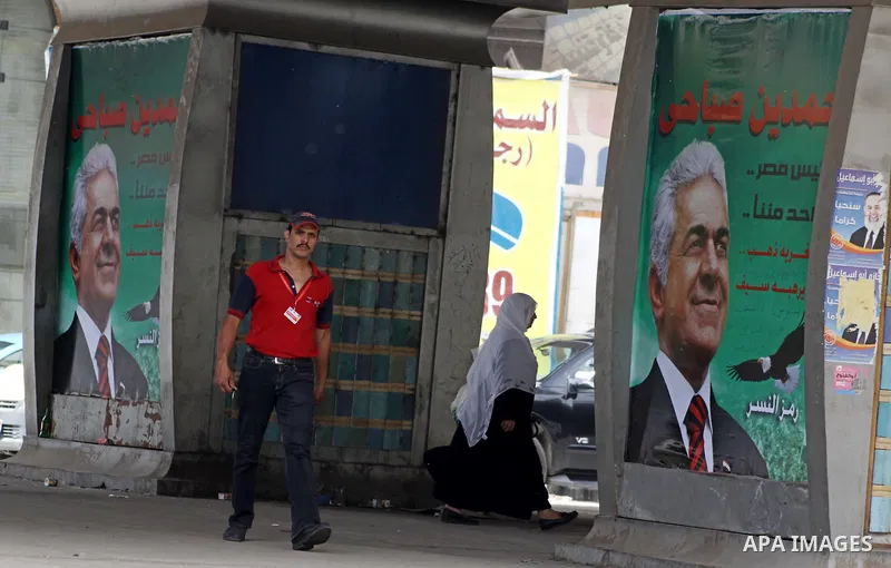 A campaign poster supporting presidential candidate Hamdeen Sabahi is posted outside a barbershop in Cairo, Egypt as people return to daily life after two days of voting in the country's presidential election Friday, May...