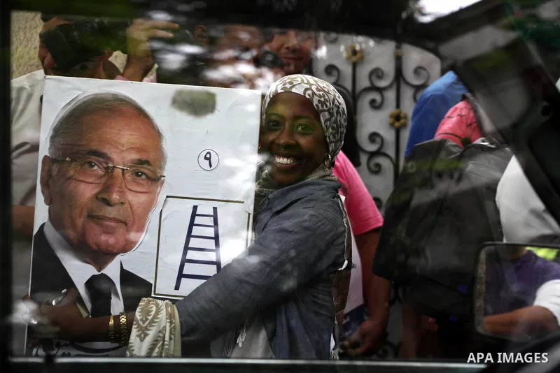 Supporters of Egyptian presidential candidate and former prime minister Ahmed Shafiq holds his poster during a press conference in Cairo on May 26, 2012. Shafiq, ousted leader Hosni Mubarak's ex-premier who is set to fac...