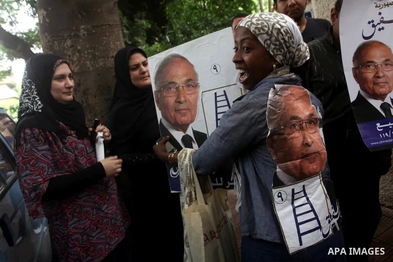 Supporters of Egyptian presidential candidate and former prime minister Ahmed Shafiq holds his poster during a press conference in Cairo on May 26, 2012. Shafiq, ousted leader Hosni Mubarak's ex-premier who is set to fac...