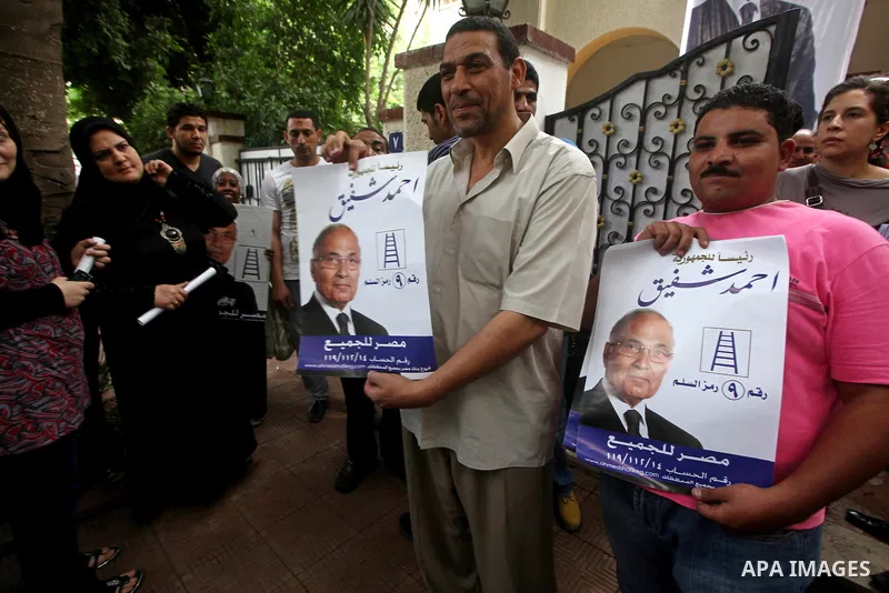 Supporters of Egyptian presidential candidate and former prime minister Ahmed Shafiq holds his poster during a press conference in Cairo on May 26, 2012. Shafiq, ousted leader Hosni Mubarak's ex-premier who is set to fac...