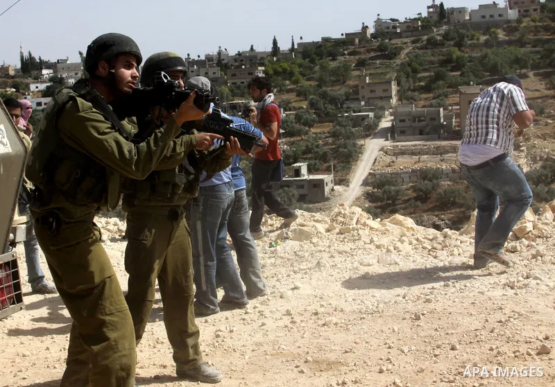 Palestinian protesters run for cover as Israeli forces fire in the air to disperse the crowd during clashes that followed the setting on fire of fields of grain and olive trees by hardline settlers from the Jewish settle...