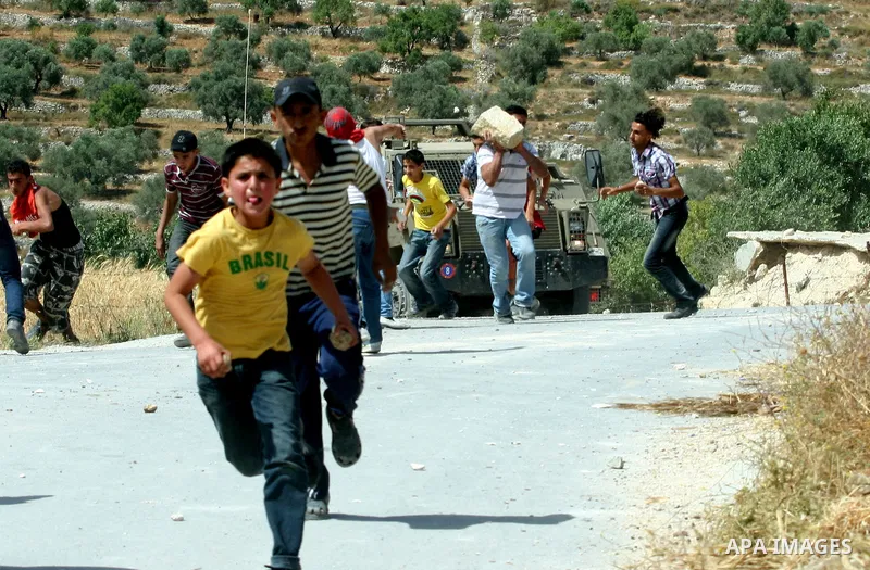Palestinian protesters run for cover as Israeli forces fire in the air to disperse the crowd during clashes that followed the setting on fire of fields of grain and olive trees by hardline settlers from the Jewish settle...