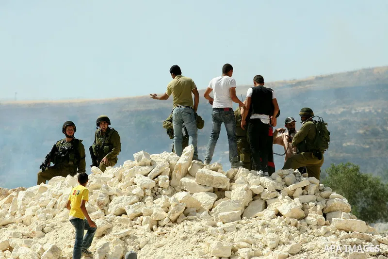 Palestinian protesters run for cover as Israeli forces fire in the air to disperse the crowd during clashes that followed the setting on fire of fields of grain and olive trees by hardline settlers from the Jewish settle...